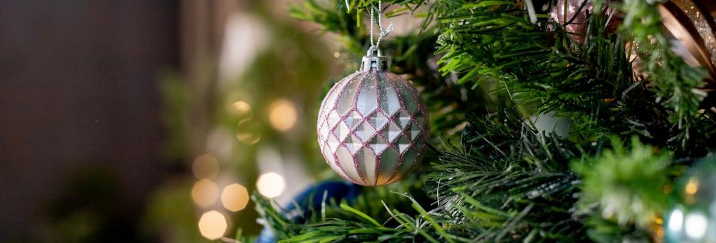 Silver and pink bauble hanging on a decorated snow tree. Christmas holiday background.