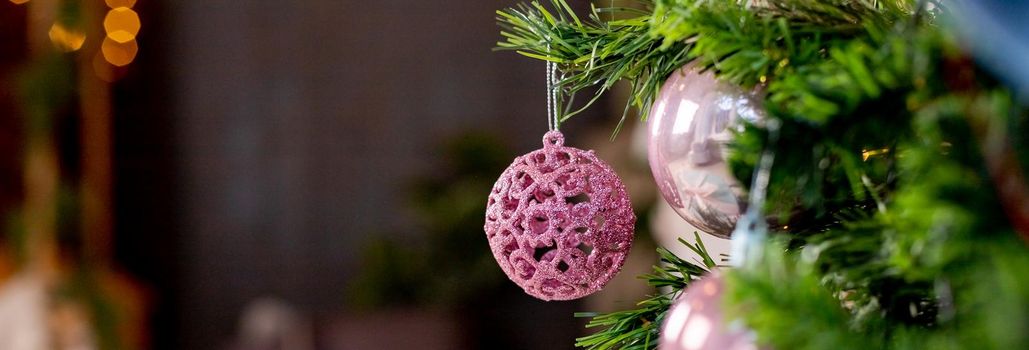 Silver and pink bauble hanging on a decorated snow tree. Christmas holiday background.