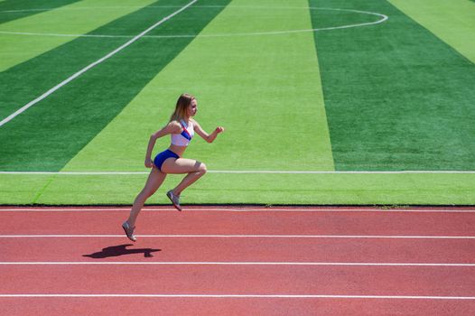 Young caucasian woman is engaged in jogging at the stadium outdoors