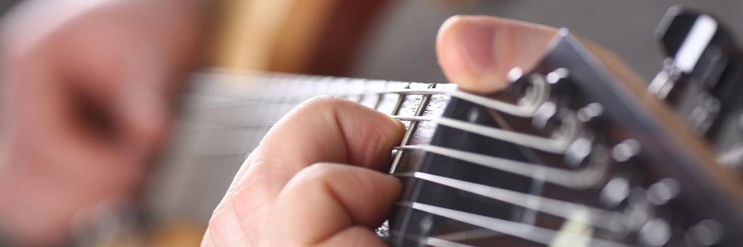 Male hands holding and playing wooden guitar. Six string training guitar and music school concept