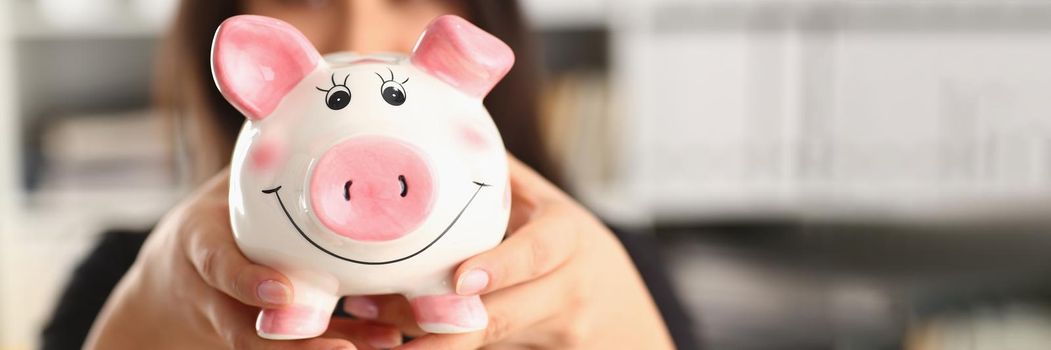 Young woman holding piggy bank in hands pink pig piggy bank. Accumulation of funds concept