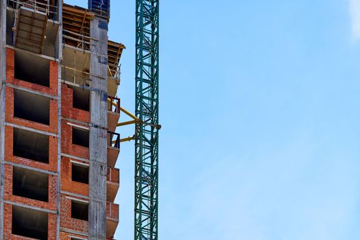 a large, tall machine used for moving heavy objects by suspending them from a projecting arm or beam. Construction high crane,building and blue cloud sky