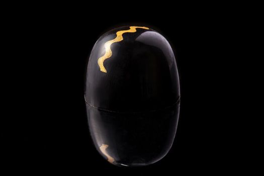 Black and gold colored luxury handmade chocolate candy on black background. Exclusive handcrafted bonbon. Product concept for chocolatier