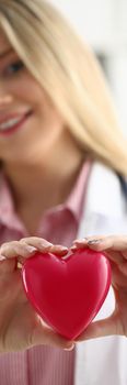 Cardiologist holds red heart in hands. Types of diseases of cardiovascular system concept