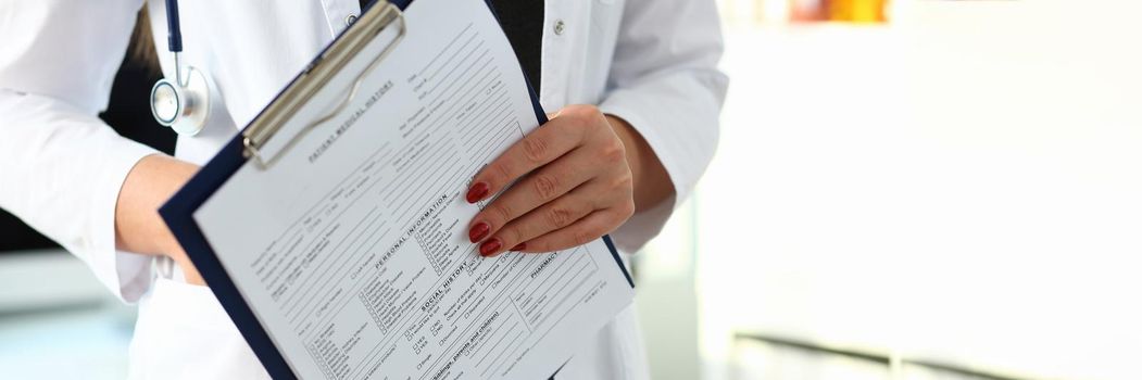 Woman doctor hand holds medical card with patient history. Medical examination and diagnosis posting concept