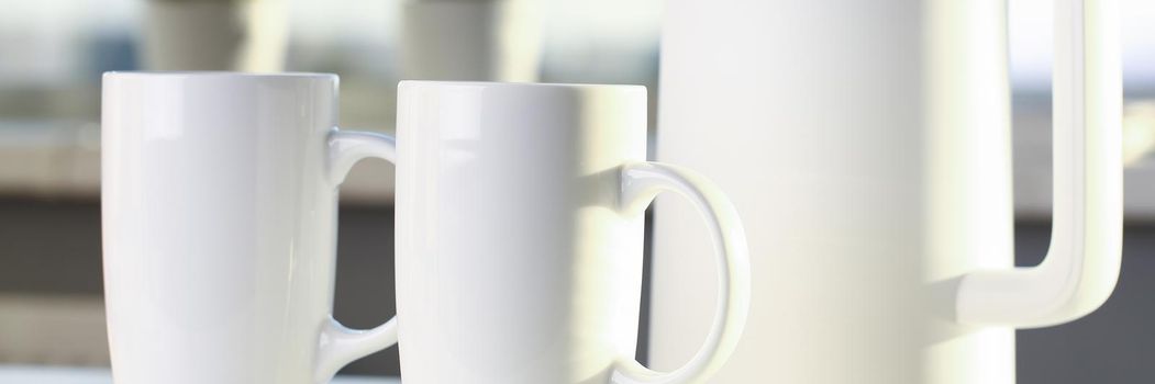 Teapot and two trendy cups are on the table for evening family tea. Stylish kitchen utensils concept