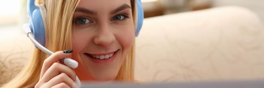 Portrait of happy young caucasian woman in headphones talking online with client via digital webcam. Remote communication concept