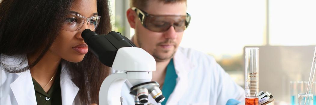 Two chemistry students conduct microscopic examinations in laboratory. Scientific research in chemical industry concept