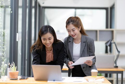 Two Young Asian businesswoman discuss with new startup project Idea presentation, analyze planning and financial statistics and investment market at office..