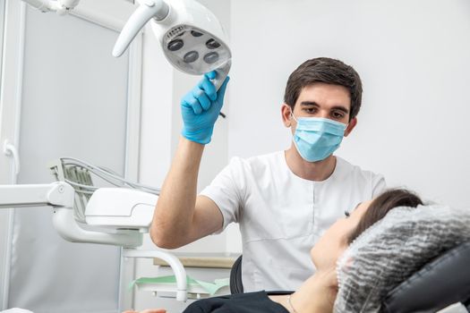 Dentist adjusting dental lamp in a dental office