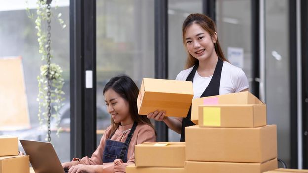 Portrait of Asian young woman SME working with a box at home the workplace.start-up small business owner, small business entrepreneur SME or freelance business online and delivery concept..