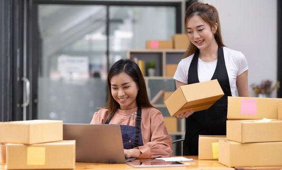 Portrait of Starting small businesses SME owners, two Asian woman check online orders Selling products working with boxs freelance work at home office, sme business online small medium enterprise.