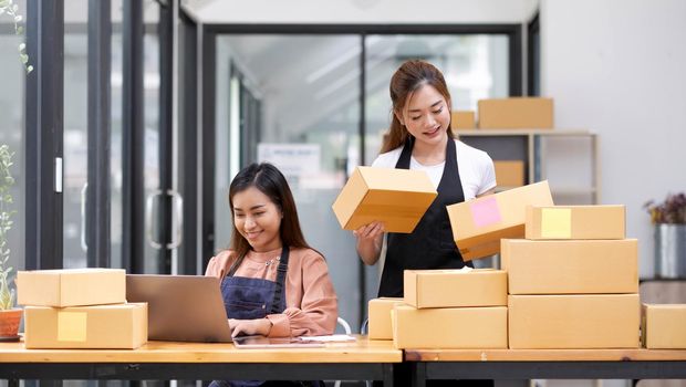 Two Asian woman owned business startup sme small business entrepreneur SME distribution warehouse with parcel mail box. SME owner in office. Online marketing and product packaging and delivery service.