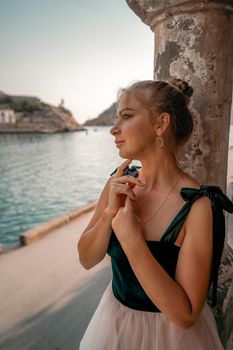 Side view portrait of a relaxed woman breathing fresh air at the seaside. She stands near the old column