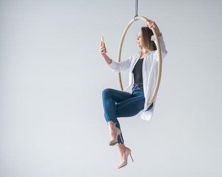 Caucasian woman gymnast on an aerial hoop takes a selfie on a smartphone