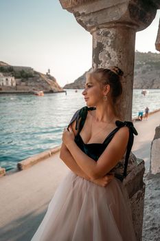 Side view portrait of a relaxed woman breathing fresh air at the seaside. She stands near the old column