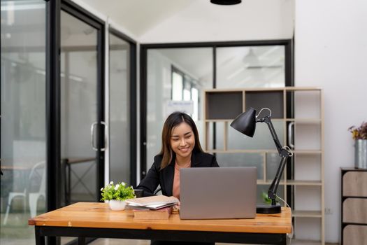 Young business asian woman working at laptop in office.