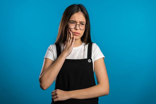 Young pretty asian woman with tooth pain on blue studio background. Toothache, dental problems, stomatology and medicine concept