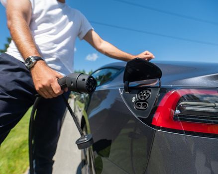 Caucasian man connect charger to electric car