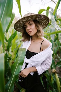 Portrait of young stylish woman in green jungle. Girl in straw hat, linen clothes. Lady looks happy and healthy, she smiles. High quality photo