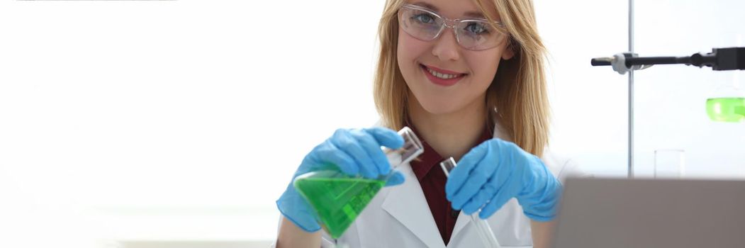 Scientist holds bottle with sample with toxic green liquid in hands in protective gloves. Toxic substances and liquids concept