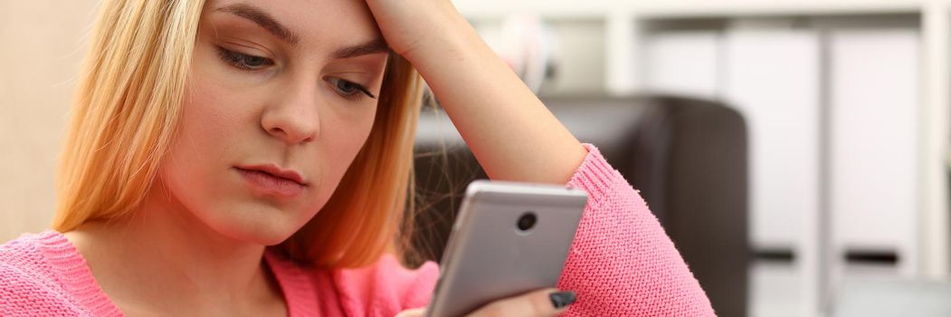 Sad woman looks at smartphone screen. Breakup and chatting concept