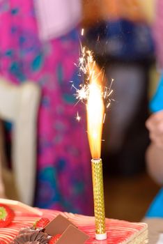 closeup of a fountain firework burning on a cake with a blurred background