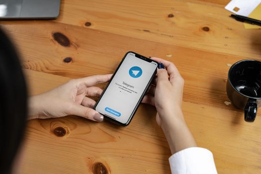 CHIANG MAI, THAILAND, AUG 26, 2022 : Woman hand holding iPhone X with social networking service Telegram on the screen. iPhone 10 was created and developed by the Apple inc