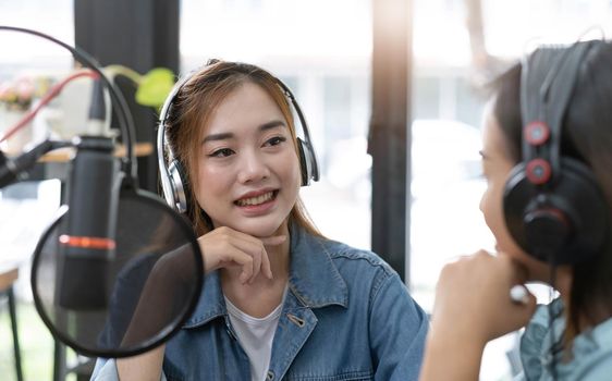 Smile two asian young woman, man radio hosts in headphones, microphone while talk, conversation, recording podcast in broadcasting at studio together. Technology of making record audio concept..