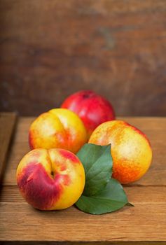 fresh nectarines with leaves on wooden background