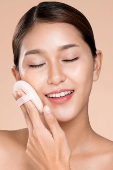 Closeup ardent woman applying her cheek with dry powder and looking at camera. Portrait of younger with perfect makeup and healthy skin concept.