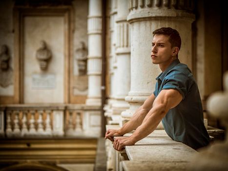 Portrait of Attractive Young Man Leaning Against Polished Marble Staircase Railing Inside Classical Building