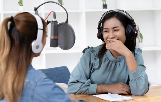 Smile two asian young woman, man radio hosts in headphones, microphone while talk, conversation, recording podcast in broadcasting at studio together. Technology of making record audio concept..