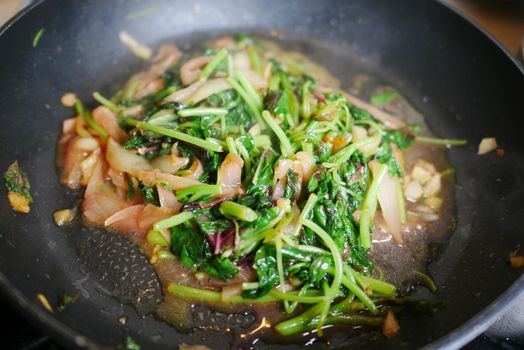 cooking green spinach in a cooking pan .