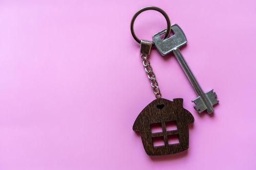 Key with a house keychain on a colored pink background. Real estate agent. Buying a house, apartment