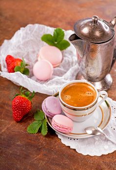 Macaroon with berries cookies and a cup of coffee on a wooden