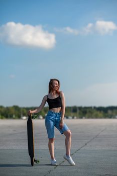 Young caucasian woman holding a long board outdoors