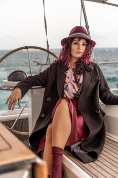 Attractive middle-aged woman at the helm of a yacht on a summer day. Luxury summer adventure, outdoor activities