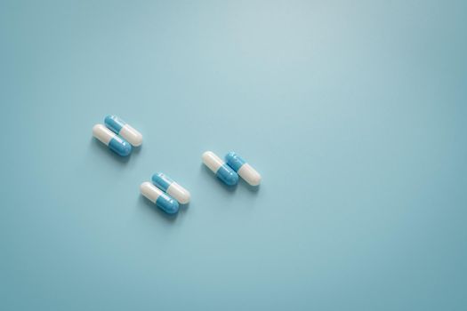 Pairs of white-blue antibiotic capsule pills on blue background. Antibiotic drug. Prescription drug. Pharmacology and recommended dose concept. Pharmaceutical industry. Medical and healthcare concept.