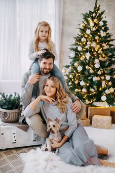 Happy family: mom, dad and pet. Family in a bright New Year's interior with a Christmas tree.