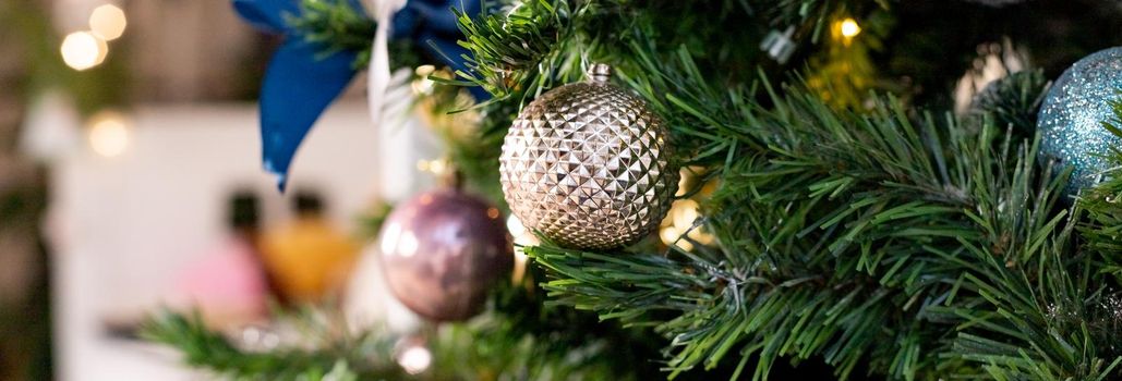 Silver and pink bauble hanging on a decorated snow tree. Christmas holiday background.