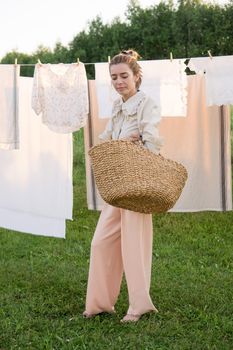 Laundry day. A woman hangs linen and towels on a tree in the courtyard of a village house. Summer cottage concept.