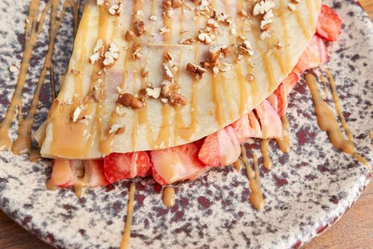 photo of delicious crepe with strawberry, walnut and decorated with cajeta. sweet crepe.