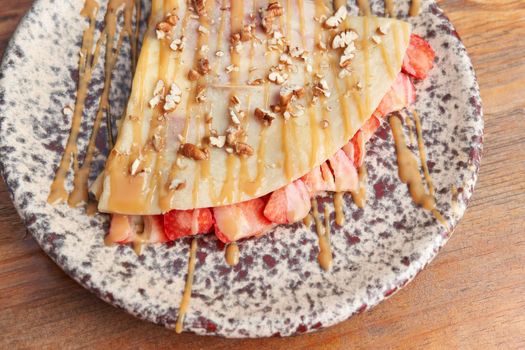 photo of delicious crepe with strawberry, walnut and decorated with cajeta. sweet crepe.