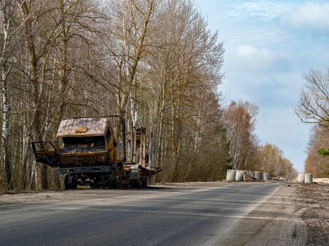 Road traffic accident of a car with fire. Car accident. Road in the forest. Damaged transport. Asphalt pavement. Traffic Laws. Military actions. Motor vehicle. Ukraine.