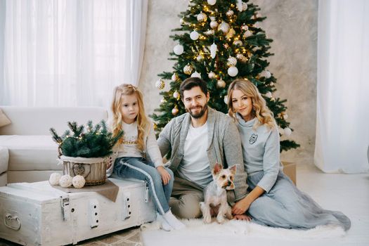 Happy family: mom, dad and pet. Family in a bright New Year's interior with a Christmas tree.