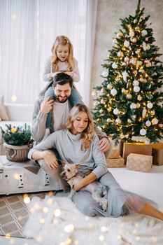 Happy family: mom, dad and pet. Family in a bright New Year's interior with a Christmas tree.