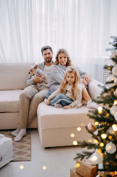 Happy family: mom, dad and pet. Family in a bright New Year's interior with a Christmas tree.