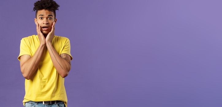 Oh no what do. Portrait of worried, anxious panicking young man feel concerned and confused, hold face and gasping anxious, staring camera alarmed, standing purple background.