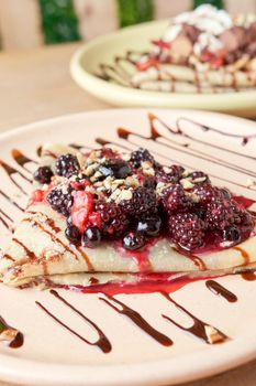 photo of delicious crepe with red berries, blackberries, blueberries, blueberries, strawberries and chocolate decoration. sweet crepe.